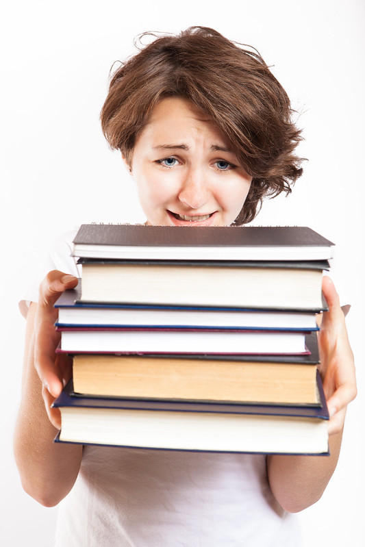 Girl warily holding a stack of books